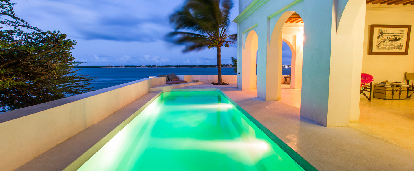 illuminated pool of the villa in Shella Beach on Lamu Island in Kenya with ocean view at dusk