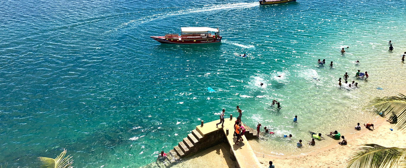 la plage animée de Shella Beach sur l’île de Lamu au Kenya avec baignade, bateaux et eau turquoise