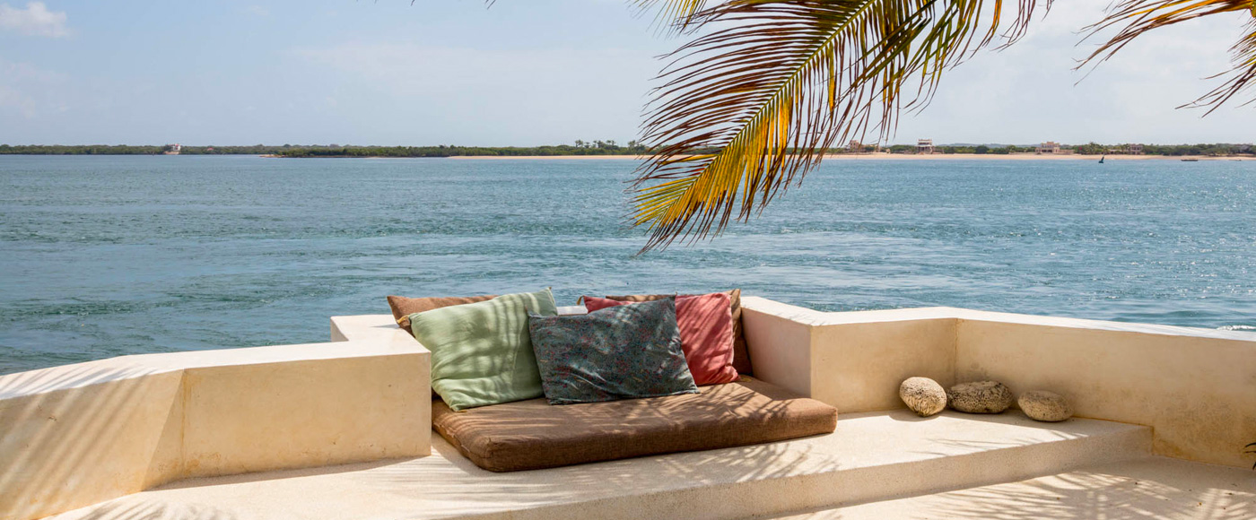 terrace of the villa in Shella Beach on Lamu Island in Kenya with cushions and palm tree facing the ocean
