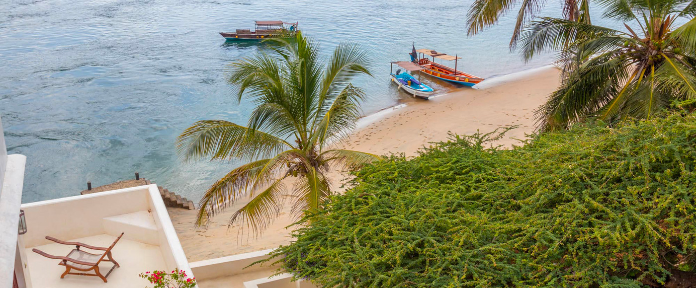 la plage shella beach bordée de palmiers sur l’île de Lamu au Kenya avec bateaux de pêche